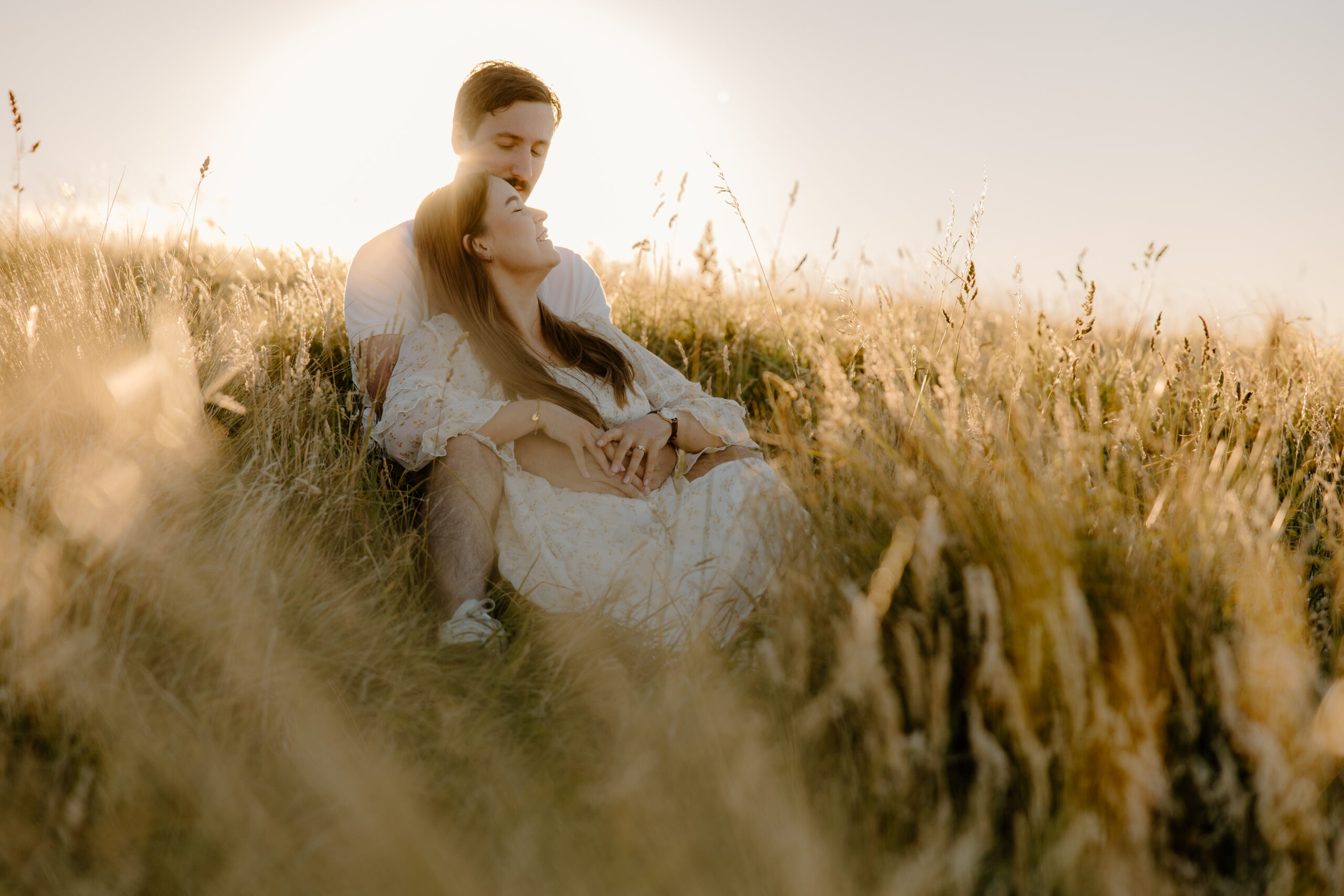 Couple sitting in the grass at Sunset in the port hills