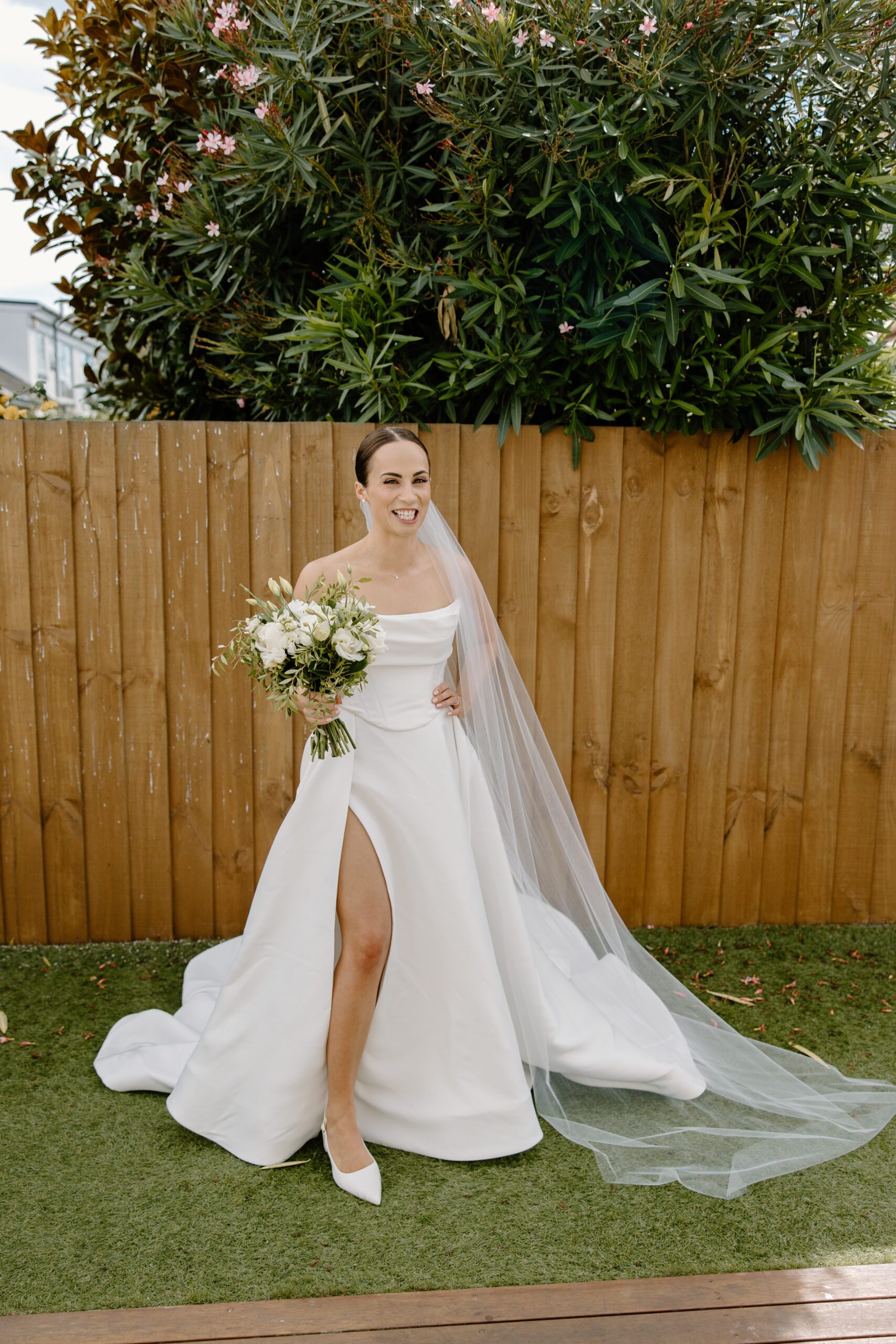 Bride standing outside with flowers before wedding ceremony