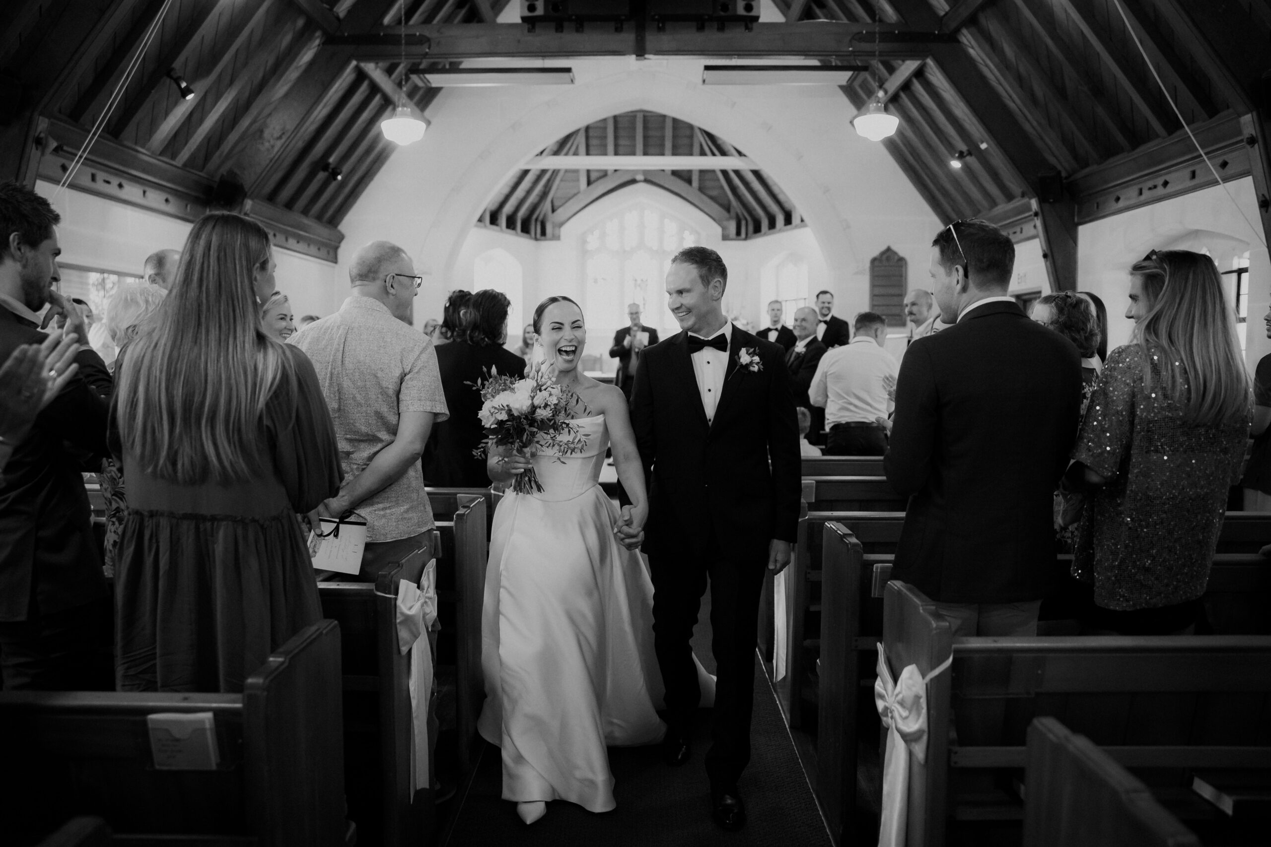 Black and White image of bride and groom walking back up the aisle after church ceremony