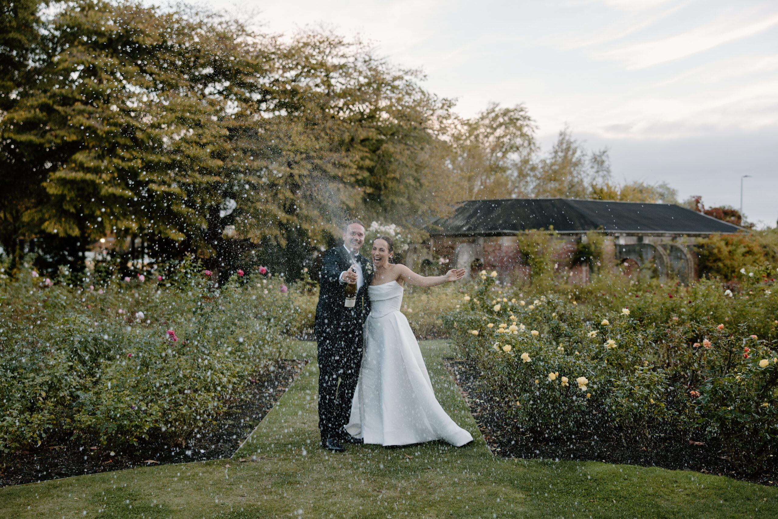 Bride and Groom spraying Champagne at Sunset in Mona Vale Gardens