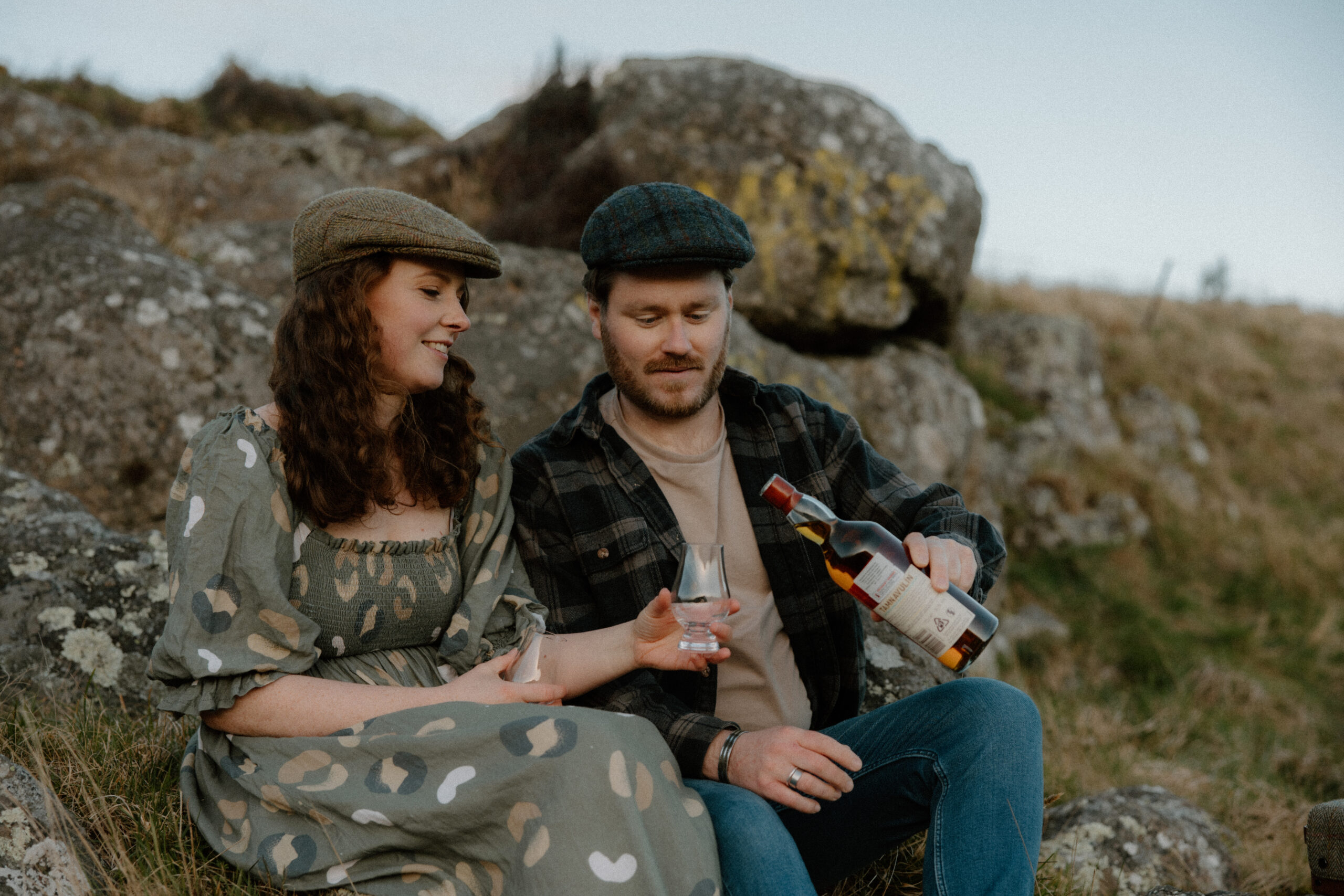 Couple drinking whisky during an engagement session at Rapaki Rock in the Port Hills, Christchurch.